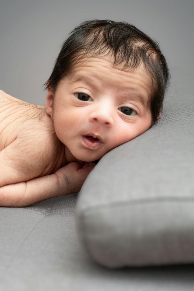 A heartwarming portrait of a newborn baby lying on soft bedding, showcasing innocence and tenderness.
